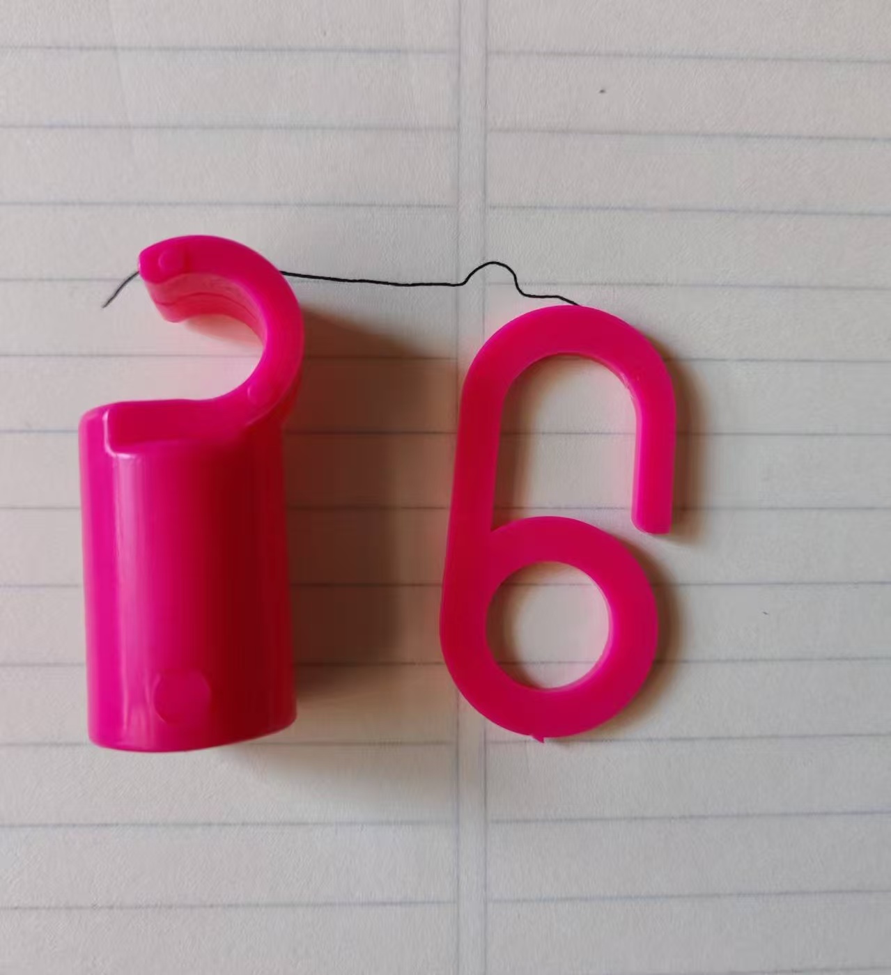 Pinke Betternet-Clips und Haken auf einer linierten Unterlage